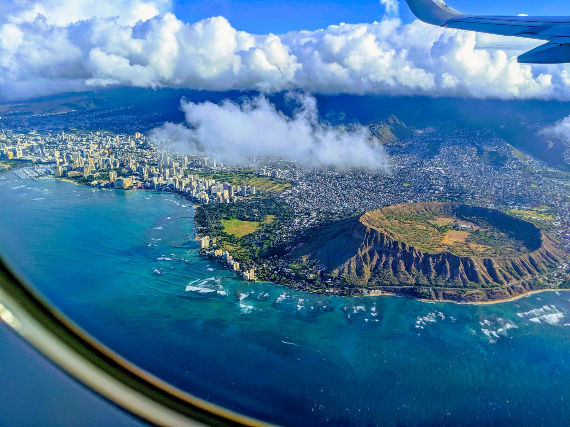 aerial view of green and brown island under blue sky and white clouds during daytime